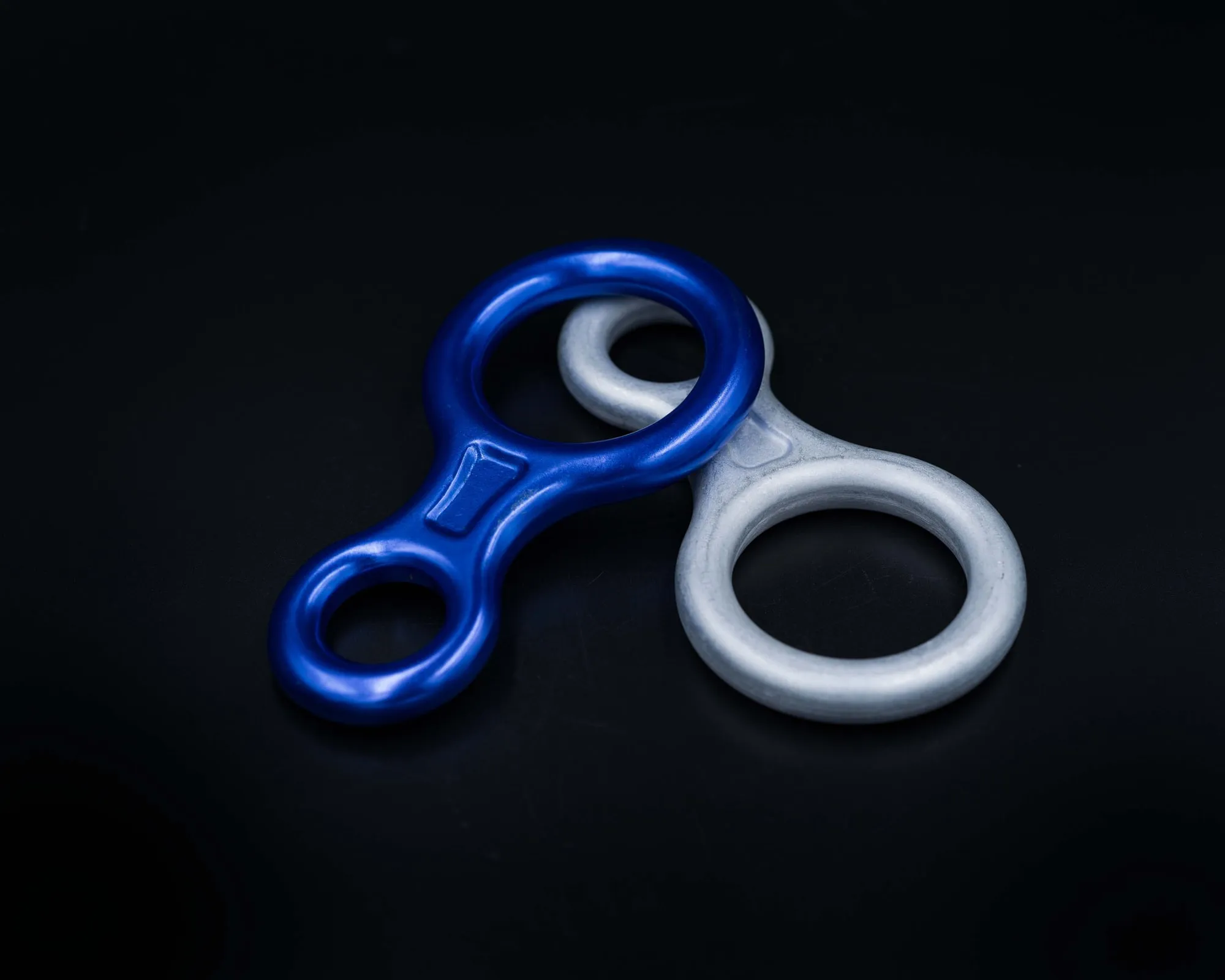 Forged aluminum figure-8 descenders, one blue anodized and one natural finish