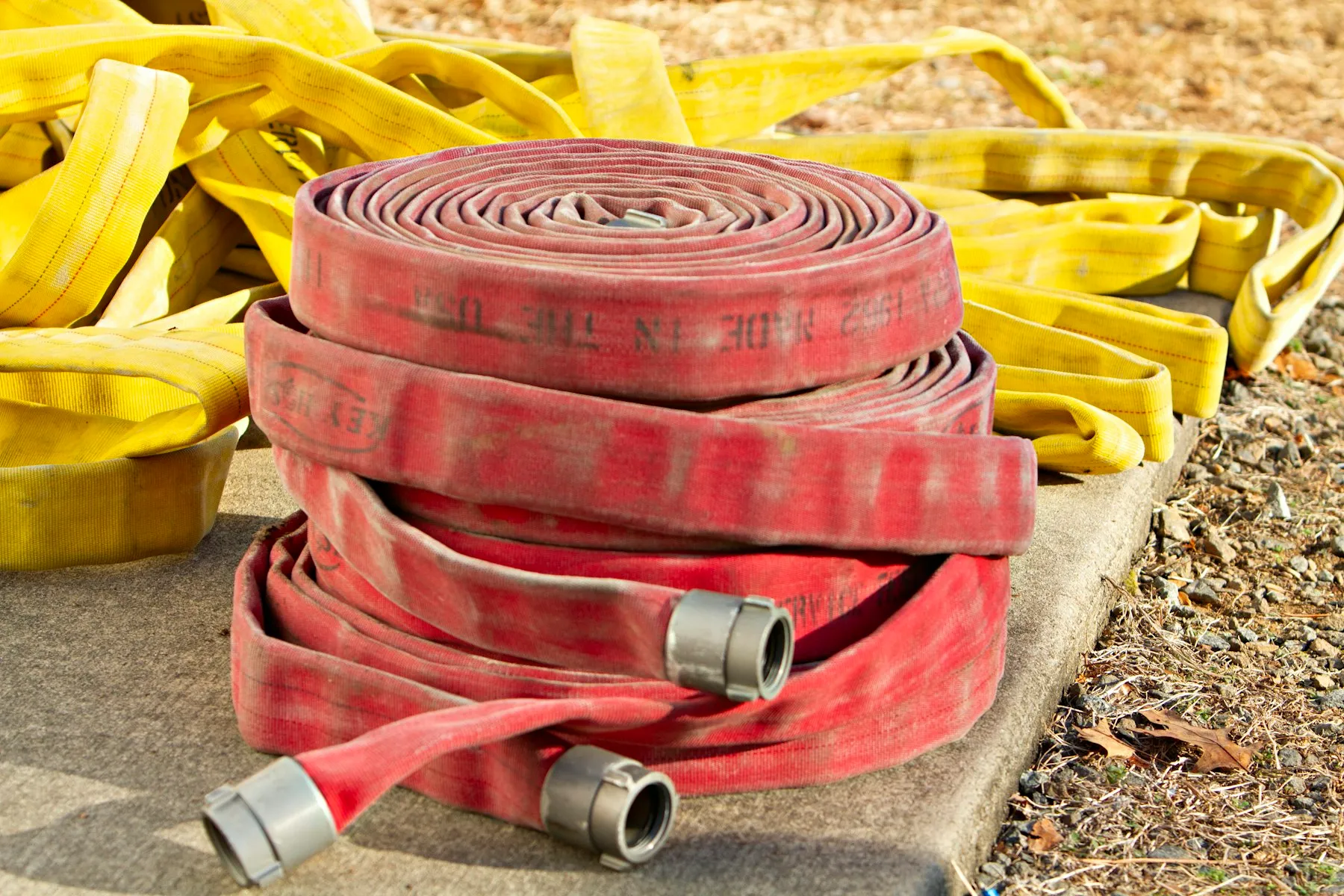 Rolled fire hoses with metal hose couplings on a concrete slab